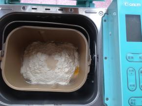 加入奶粉、面粉，在面粉最顶端加入酵母。然后将面包桶放入到东菱4706W面包机内，选择和面10分钟