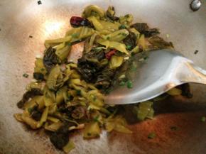 锅里加一点油烧热后放入姜蒜片和部分葱花小火炒出香味，再加入酸菜翻炒出香味。