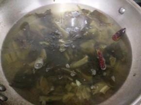 锅里加一点油烧热后放入姜蒜片和部分葱花小火炒出香味，再加入酸菜翻炒出香味。