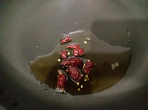 平底锅中加入适量食用油，放入切段的干辣椒，小火把油烧热。