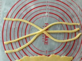 将其他派皮也擀簿，切出3条，0.8cm宽，28cm长的长条。如图在中间交叉摆放。