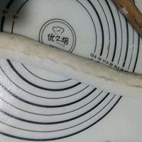 再把下部的面片边压薄后提起抻长向上卷折，接口处用手捏紧。（捏不紧烤制过程中会裂开）