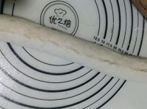 再把下部的面片边压薄后提起抻长向上卷折，接口处用手捏紧。（捏不紧烤制过程中会裂开）