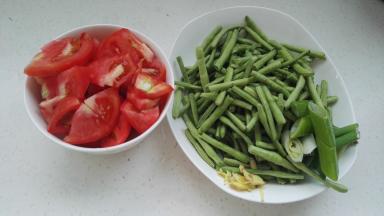 准备好的原料。豆角用手掰成段，姜切丝，葱切段。西红柿切小块。