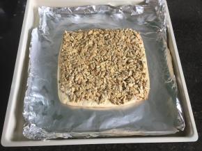 铺在面饼上抹匀开来，放进预热好的烤箱内继续165度上下火中层烤20分钟左右，至表面金黄即可，完全冷却后切块食用；