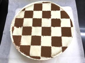 第二天从冰箱中拿出用热毛巾捂一下模具边缘，即可轻松脱模。用白纸刻出棋格，再筛上可可粉。