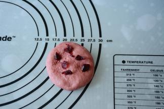 取一红色面团压扁，加入少量切碎的蔓越莓。