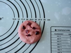 取一红色面团压扁，加入少量切碎的蔓越莓。