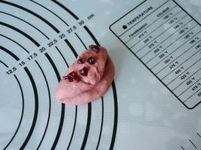 在将红色面团对折一下，再次加入少量蔓越莓，包好滚圆。