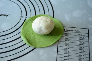 将包好的白色面团放在绿色面皮中间。