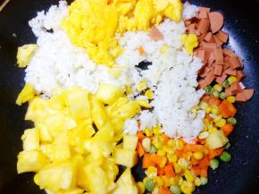 把米饭倒入一起翻炒，米饭稍微打散后，再把火腿肠粒、菠萝粒和炒好的鸡蛋 倒入锅中，因为我的米饭是刚煮晾凉的，就和鸡蛋、菠萝等同时下锅了。