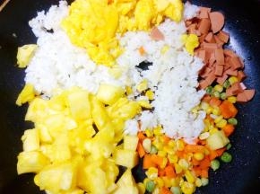 把米饭倒入一起翻炒，米饭稍微打散后，再把火腿肠粒、菠萝粒和炒好的鸡蛋 倒入锅中，因为我的米饭是刚煮晾凉的，就和鸡蛋、菠萝等同时下锅了。