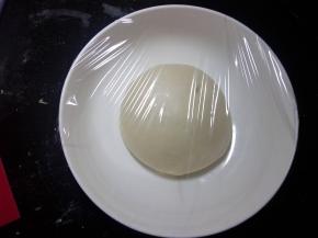 面团在操作台上，整理光滑。容器底部抹油，面团置于容器盖保鲜膜进行一发。