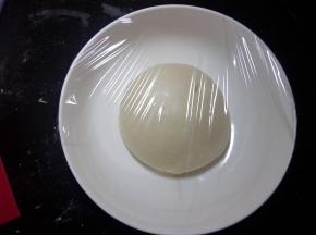 面团在操作台上，整理光滑。容器底部抹油，面团置于容器盖保鲜膜进行一发。