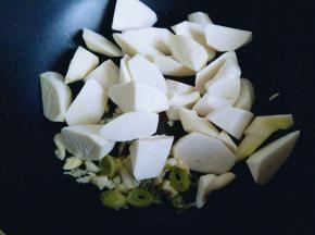 锅中加入切好的葱，蒜，炒香，有香味后加入切好的茭白块煸炒。