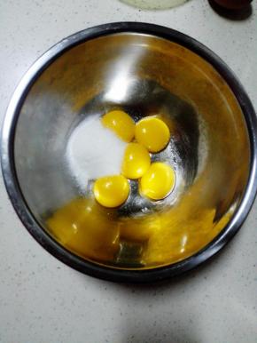 分离蛋白和蛋黄，蛋黄内加入30克细砂糖，用手动打蛋器搅打至糖融化