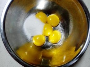 分离蛋白和蛋黄，蛋黄内加入30克细砂糖，用手动打蛋器搅打至糖融化