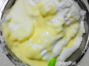 将蛋黄糊全部倒入蛋白霜盆中，翻拌均匀