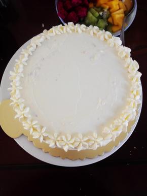 放上第二块蛋糕胚，表面和四周全部抹上淡奶油，并用裱花嘴在表面挤上一圈小花