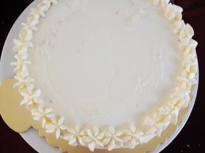 放上第二块蛋糕胚，表面和四周全部抹上淡奶油，并用裱花嘴在表面挤上一圈小花