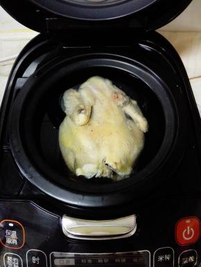 把鸡捞出，放入电饭煲中，加入没过鸡的清水