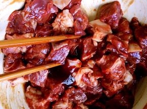3，牛肉块装碗里，放少许盐拌一下，倒入烧烤酱腌制两个小时。