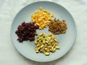 开心果用擀面杖碾碎，蔓越莓、芒果干、葡萄干切碎