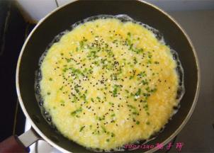 在蛋液将要凝固时，撒上黑芝麻和香葱末（这期间一直用小火煎制）；