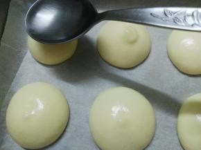 裱花袋尖端剪开口，在铺了油纸的烤盘上挤出大小合适的圆形，用勺子将表面稍稍抹平