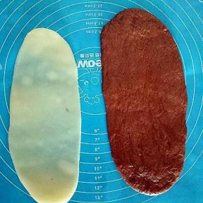 取一个发酵好的面团擀成椭圆形，取一份麻薯擀成比面团稍微小些的椭圆形