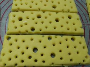 将面团擀开成厚约8mm的片状，用吸管戳出小孔状，再用粗吸管随意戳出大孔状后切成长方块