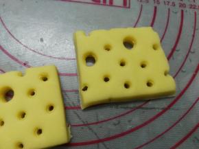 将面团擀开成厚约8mm的片状，用吸管戳出小孔状，再用粗吸管随意戳出大孔状后切成长方块