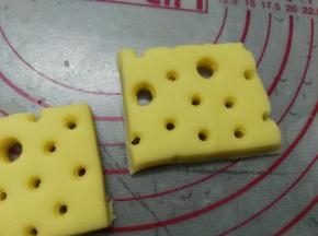 将面团擀开成厚约8mm的片状，用吸管戳出小孔状，再用粗吸管随意戳出大孔状后切成长方块