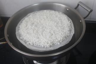 放蒸格上用蒸格布盖住，把泡洗好的糯米均匀铺上去。