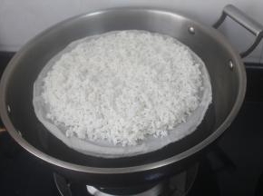放蒸格上用蒸格布盖住，把泡洗好的糯米均匀铺上去。