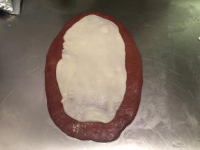 案板洒少许干粉，将主面团擀成椭圆形，麻薯分成3份，也分别擀成椭圆形，叠放在主面团上面