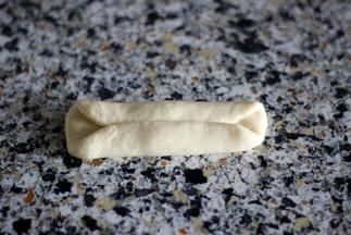 9. 取一块面团，擀成牛舌状，对折