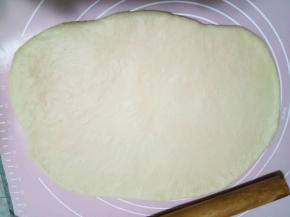 面团用擀面杖排气，然后擀成一个长方形的大面片。