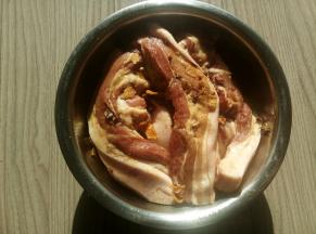 将猪肉放入盆内，翻动几下，让其裹上腌制料。