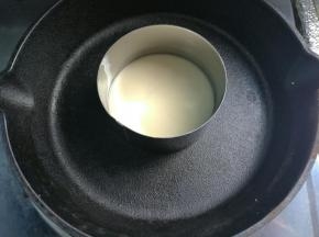 转小火，用一个圆形慕斯圈，放在锅中间（没有慕斯圈可以直接放在锅里，让面糊自然流动呈圆形），舀一勺面糊，倒入慕斯圈中，这样做出来的铜锣烧很圆，不必担心面糊流动而不圆影响美观。