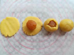 取一个酥皮按扁放上凤梨馅，用左手虎口位置包圆馅料收圆面团