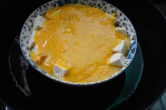 将做好的蛋黄汁淋在豆腐上。上锅蒸5分钟就可以啦。出锅后撒上葱，将肉豆腐和蛋黄拌均匀就可以吃啦。