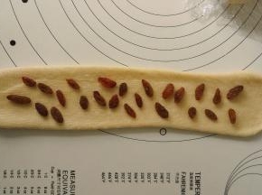 再次擀长后摆上葡萄干，然后从上往下卷起，卷好的圈数宜2.5个圈