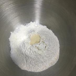 全麦粉与高筋面粉混合，盐和糖对角线放置，中间戳一孔，倒入活性干酵母