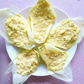 把玉米糊糊倒在玉米嫩叶上，摆放在盘子里。