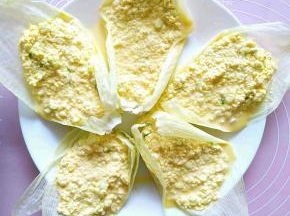 把玉米糊糊倒在玉米嫩叶上，摆放在盘子里。