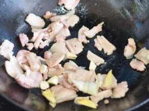 锅里倒入少量油，放入五花肉翻炒，同时放入葱、姜、蒜。