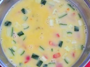 将鸡蛋打散，蛋液里加少许盐，放入切丁的黄瓜、切碎的圣女果。