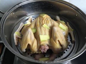 4.浸泡的花椒水全部倒入蒸锅内，鸡放在蒸架上，表面放20g生姜片，隔水蒸半小时，蒸熟等完全冷却后放冰箱冷藏一小时；