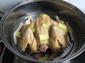 4.浸泡的花椒水全部倒入蒸锅内，鸡放在蒸架上，表面放20g生姜片，隔水蒸半小时，蒸熟等完全冷却后放冰箱冷藏一小时；